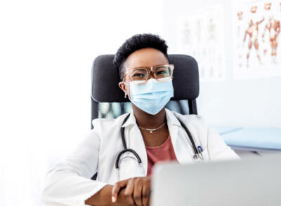 istockphoto-1320469122-612x612 Portrait of a smiling young African American female doctor wearing a face mask while sitting at her office.